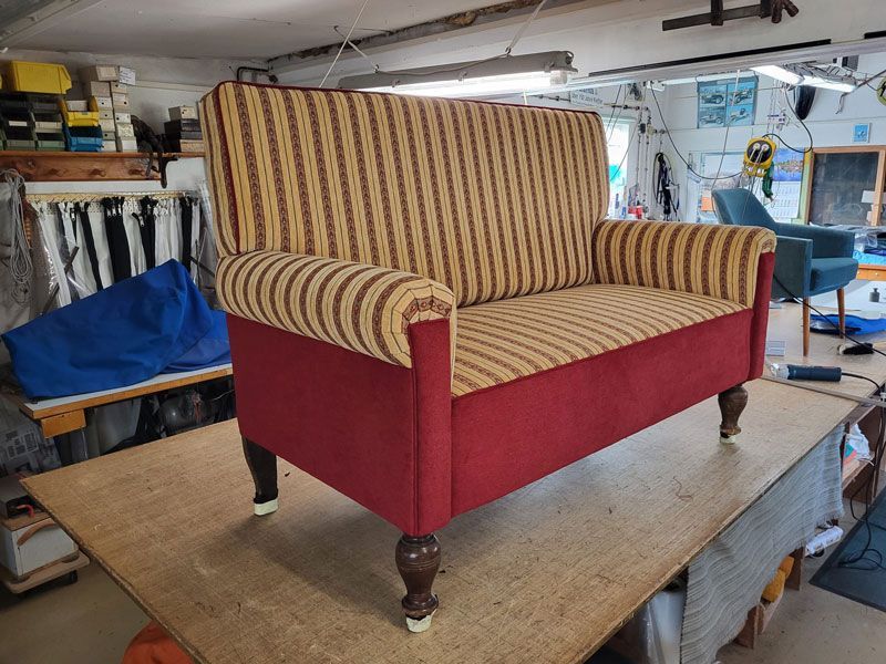 Auf einem Holztisch steht ein rot-gelb gestreiftes Sofa.