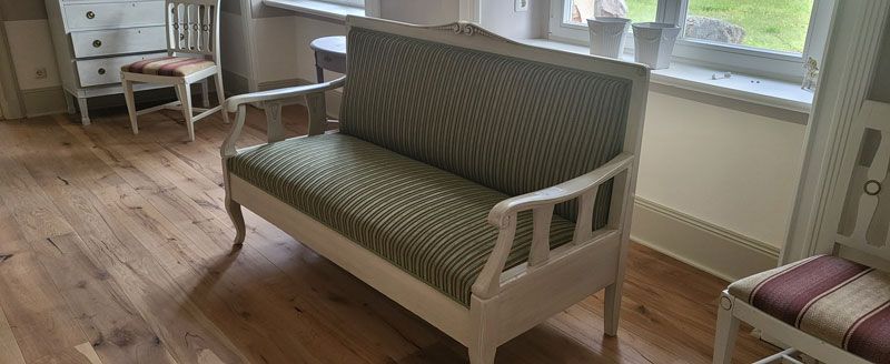 Ein weißes Sofa steht in einem Wohnzimmer neben einem Fenster.