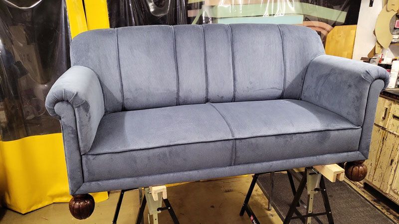 In einem Zimmer steht auf einem Tisch ein blaues Sofa.