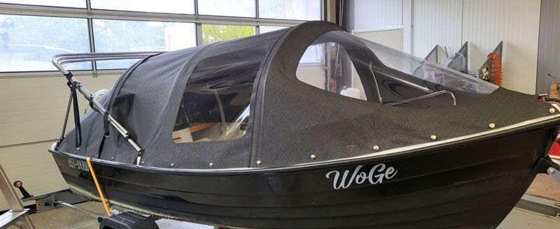 In einer Garage steht ein kleines Boot mit einem Verdeck.