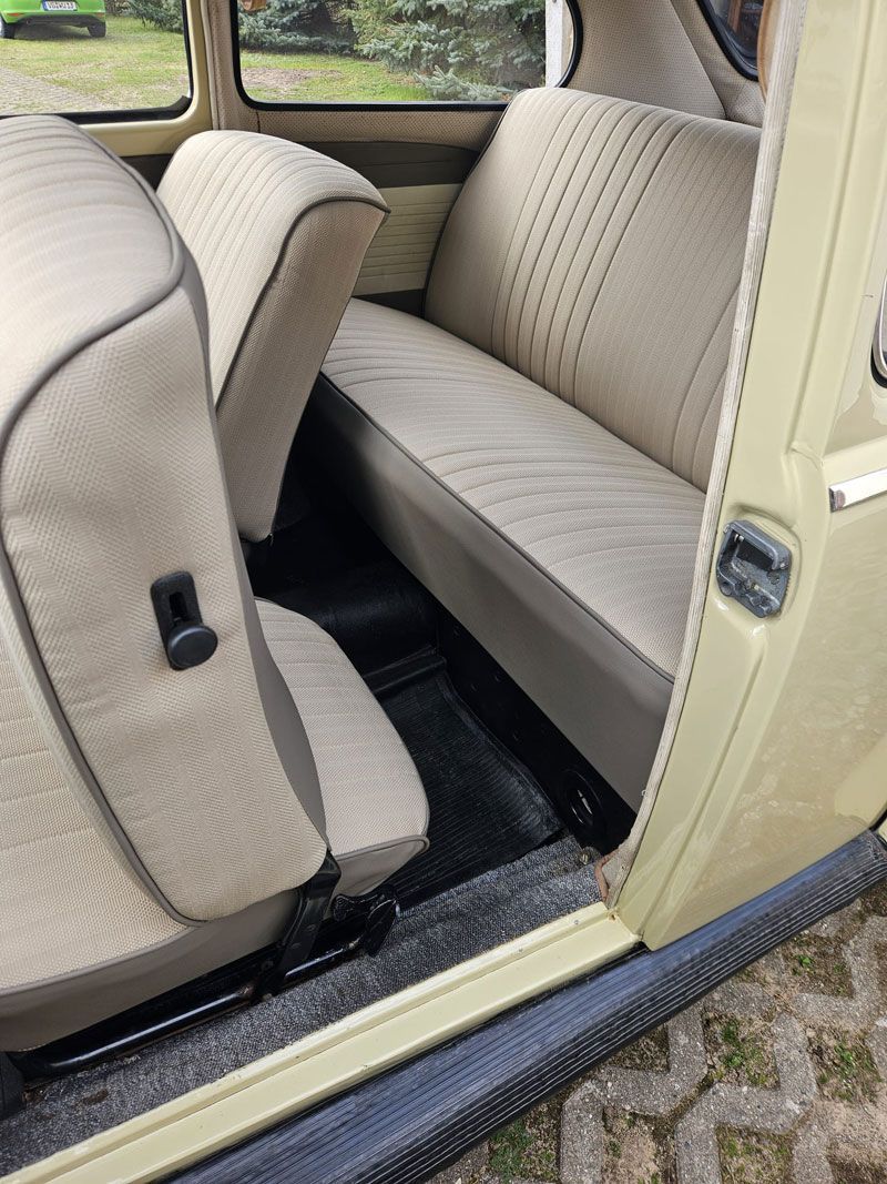 Der Rücksitz eines gelben Autos mit offener Tür.