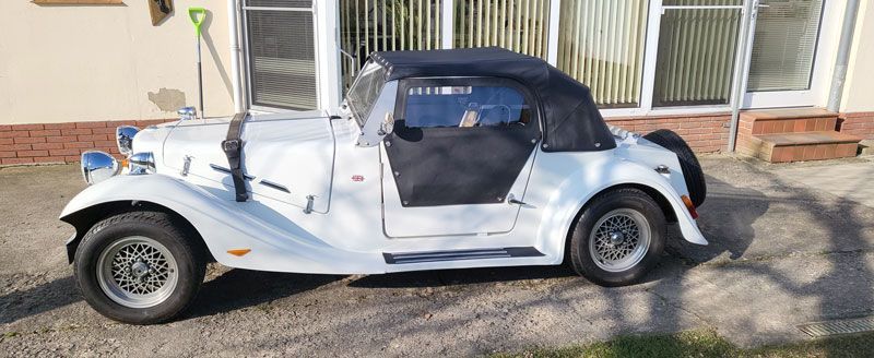 Ein weißes Auto mit schwarzem Dach steht vor einem Haus.