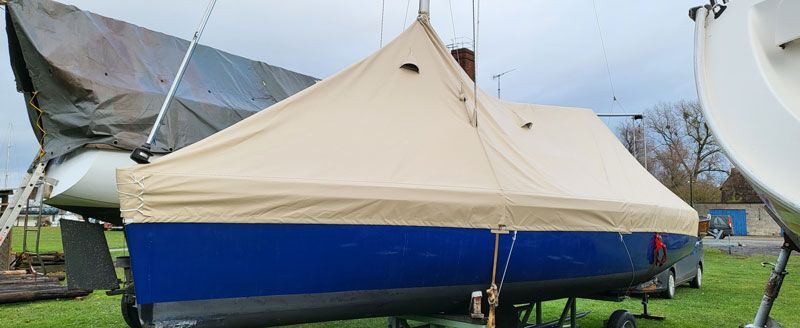 Auf einem Feld liegt ein Boot mit einem Zelt darauf.