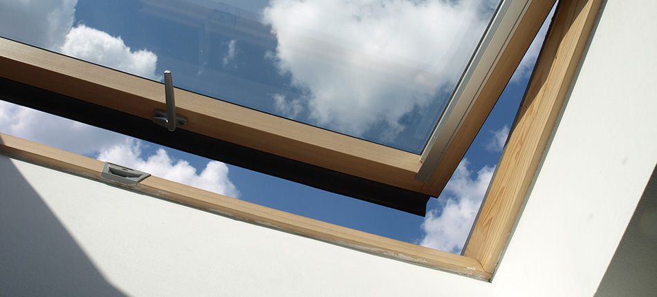 Fenêtre de toit de type Velux entrouverte sur un ciel bleu