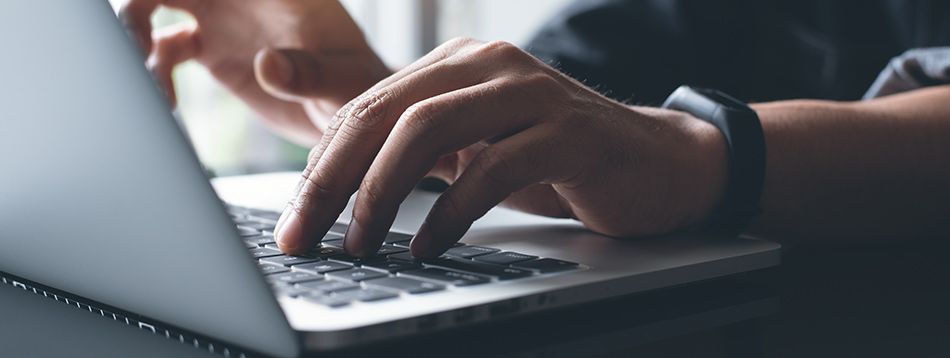 Homme avec la main posée sur le clavier d'un ordinateur portable