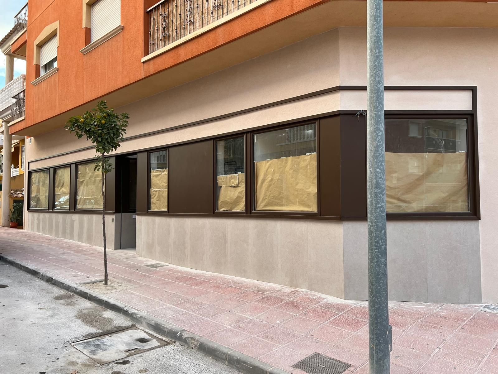 Pasillo de oficina moderno con paredes de vidrio, paneles reflectantes en el techo e iluminación brillante en el techo.