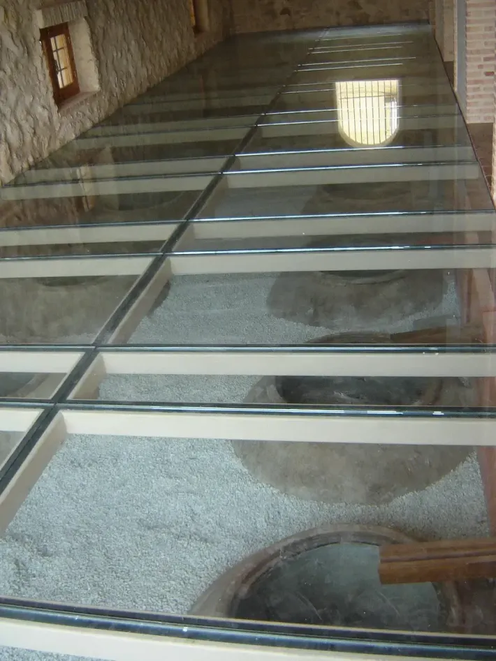 Instalación de paneles de vidrio en el suelo de un patio exterior, con dos trabajadores cerca.
