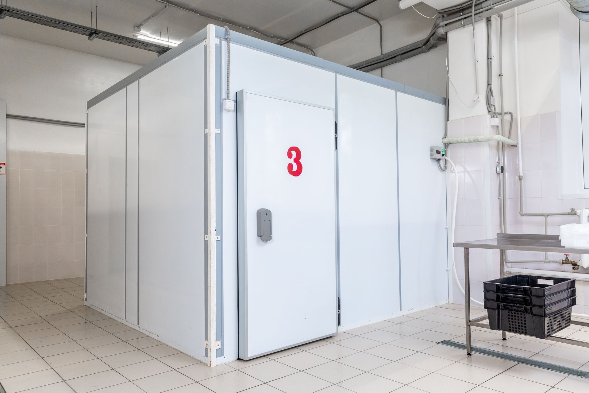 Grande chambre froide industrielle blanche avec une porte numérotée à l'intérieur d'une installation carrelée