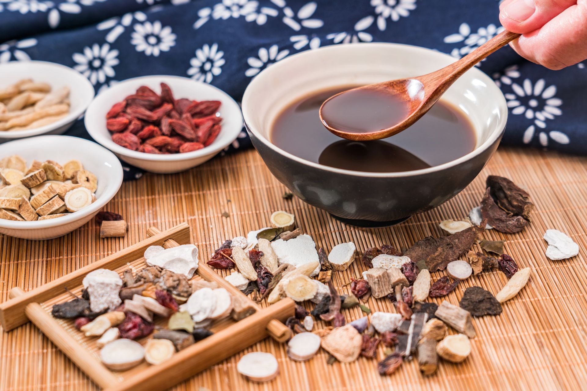 Une personne tient une cuillère en bois dans un bol de soupe.