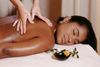 Spa massage therapy with hands on a woman’s back, beside a small flower and candle