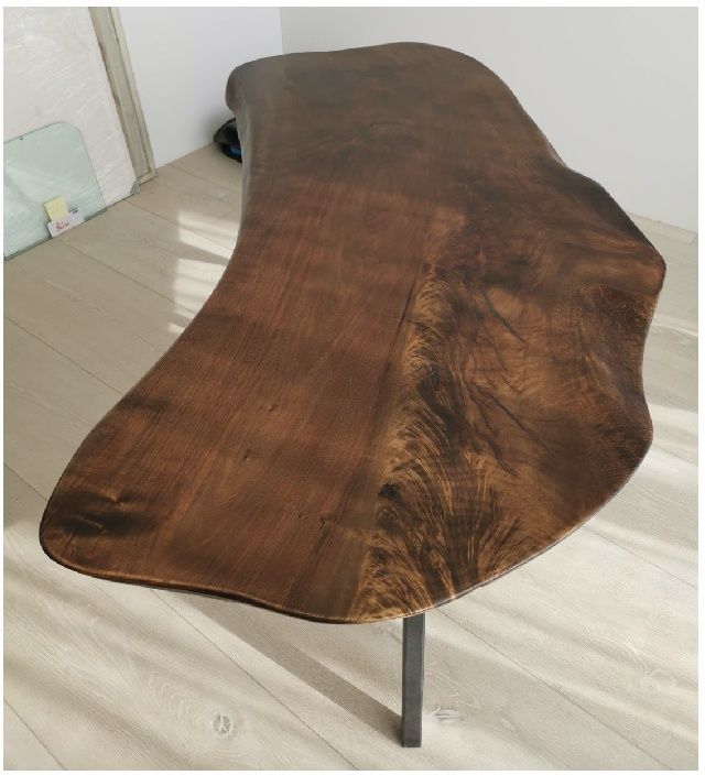 Ein Tisch aus Massivholz mit dunkelbrauner Oberfläche und Stahlbeinen in einem Zimmer.