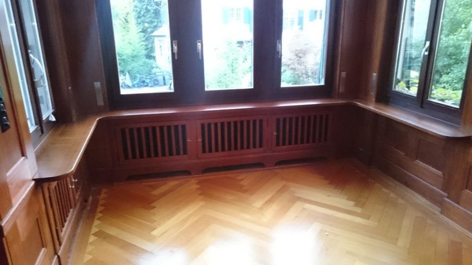 Fensterbank mit Holzvertäfelung und eingebautem Heizkörper, Blick ins Grüne. Fischgrätparkett.