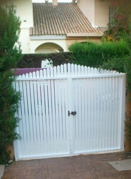 Una puerta blanca con manija negra está frente a una casa.