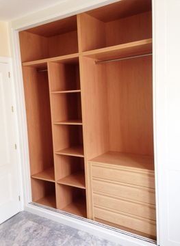 Un armario con estantes y cajones de madera en un dormitorio.