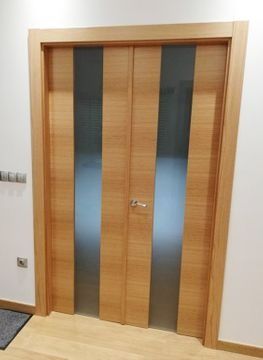 Una puerta de madera con paneles de vidrio en un pasillo.
