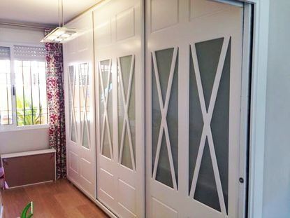 Un gran armario blanco con puertas correderas en una habitación.