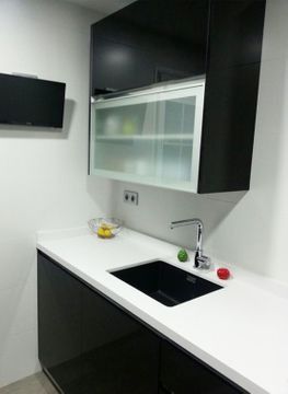 Una cocina con gabinetes negros y un fregadero negro.