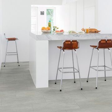 Una cocina con encimera de mármol y tres taburetes de bar.