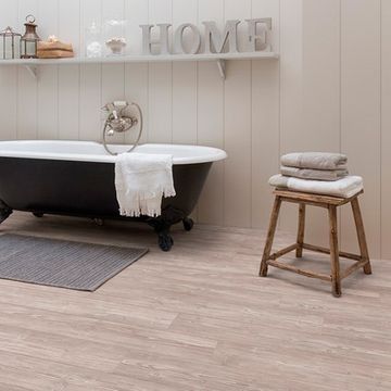 Un baño con bañera, taburete, toallas y estantería.