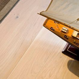 Un modelo de un velero está sentado sobre un piso de madera.