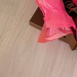Un par de zapatos en una caja con papel de seda rosa en el suelo.