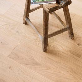 Un taburete de madera está sobre un piso de madera al lado de una revista.