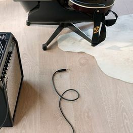 Una guitarra está sentada en una silla al lado de un amplificador.