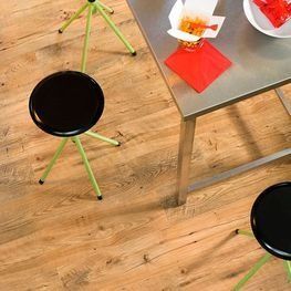 Un suelo de madera con taburetes y una mesa con comida encima.