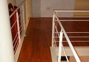 Una escalera con suelo de madera y barandilla blanca.