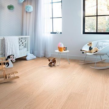 Una habitación infantil con cuna, mecedora, mesa y caballo balancín.