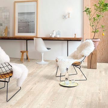 Una sala de estar con piso de madera, sillas, una mesa y una planta.