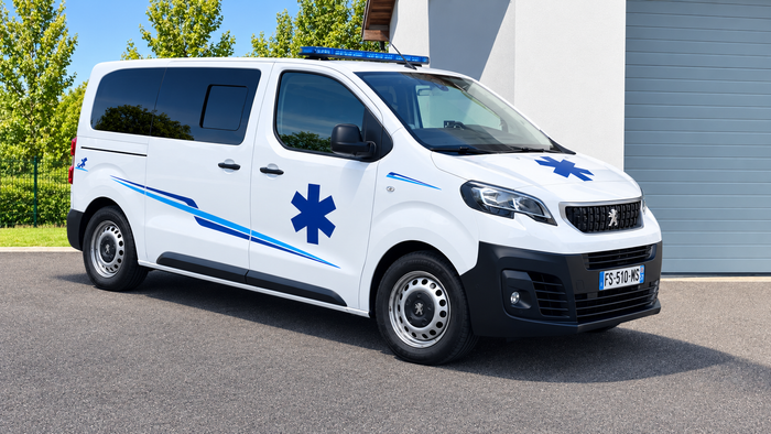 Ambulance blanche aux gyrophares bleus roulant dans une rue en ville