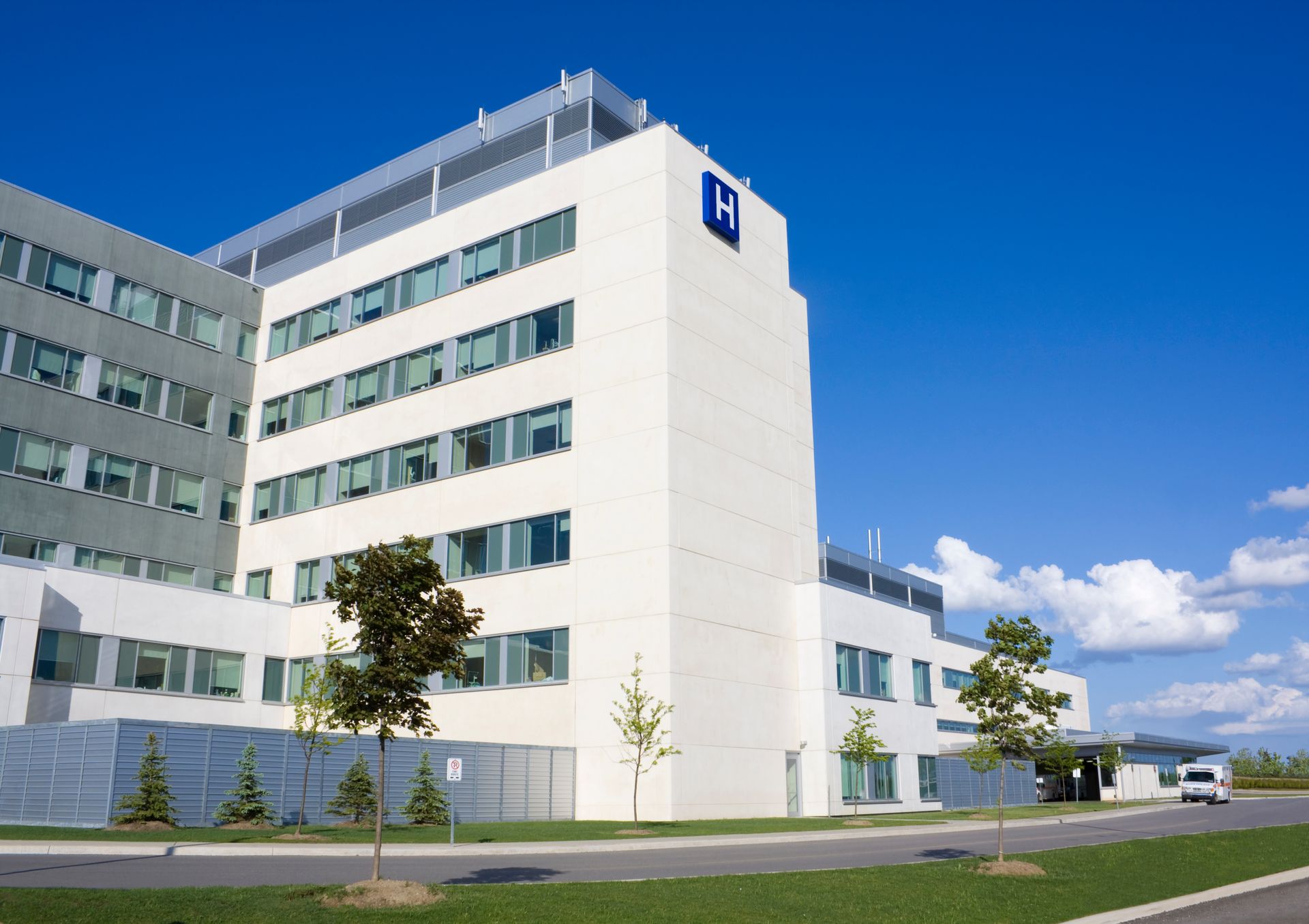 Bâtiment hospitalier moderne blanc avec une enseigne bleue sous un ciel bleu dégagé