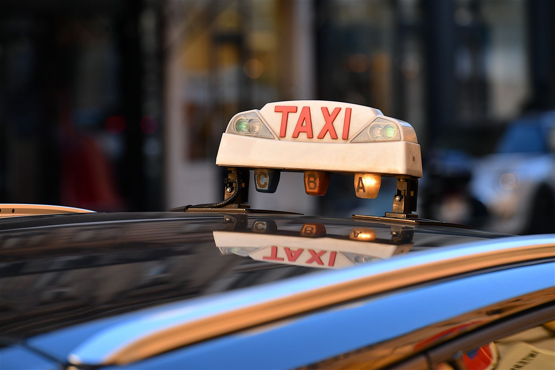 Mumignon de taxi sur le toit d’une voiture, avec une rue urbaine floue en arrière-plan