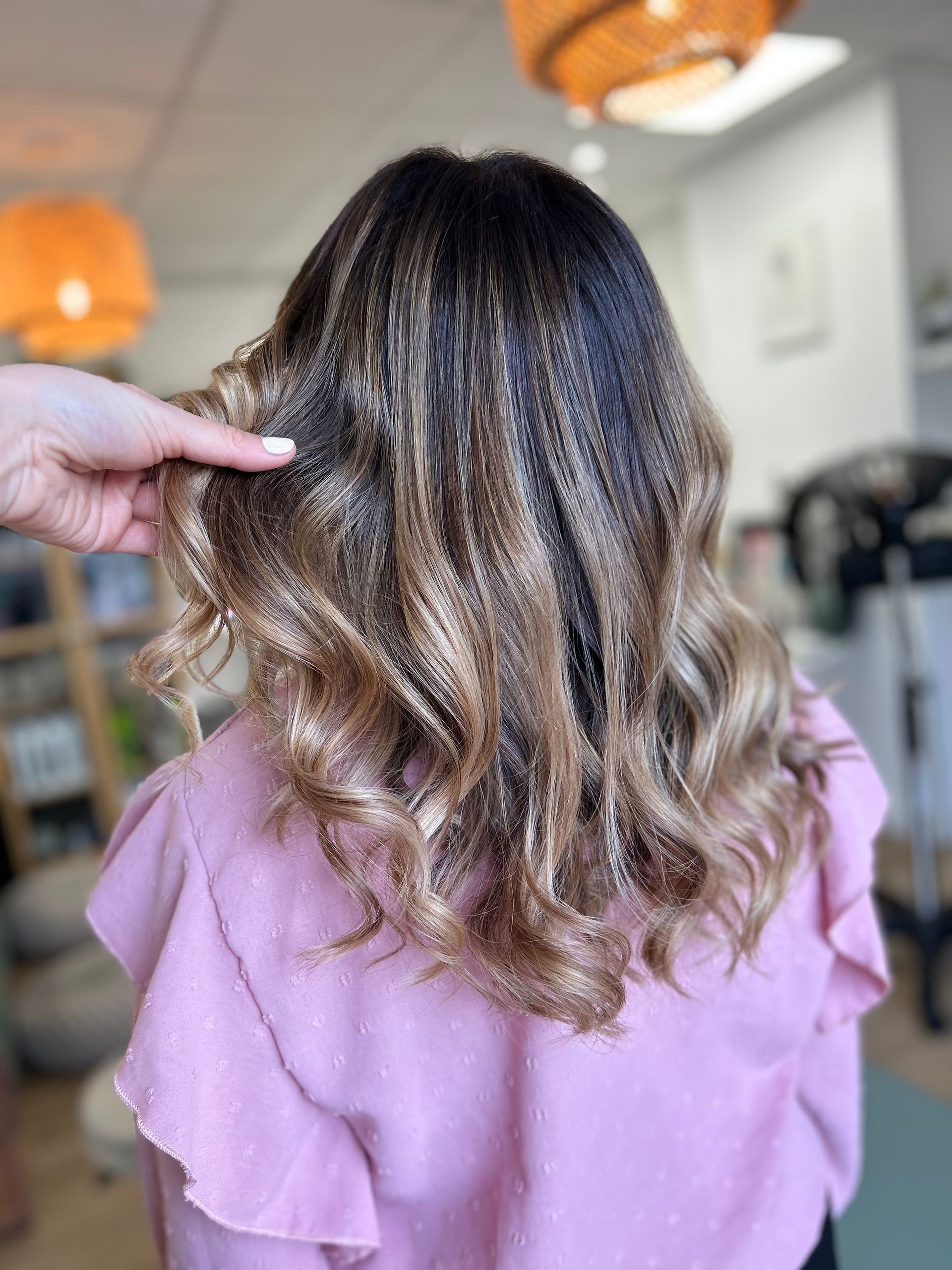 Cheveux longs, châtains et ondulés, mèches claires sur le bas