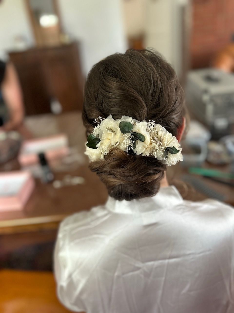 Coiffure d'évènement, chignon bas avec des fleurs blanches