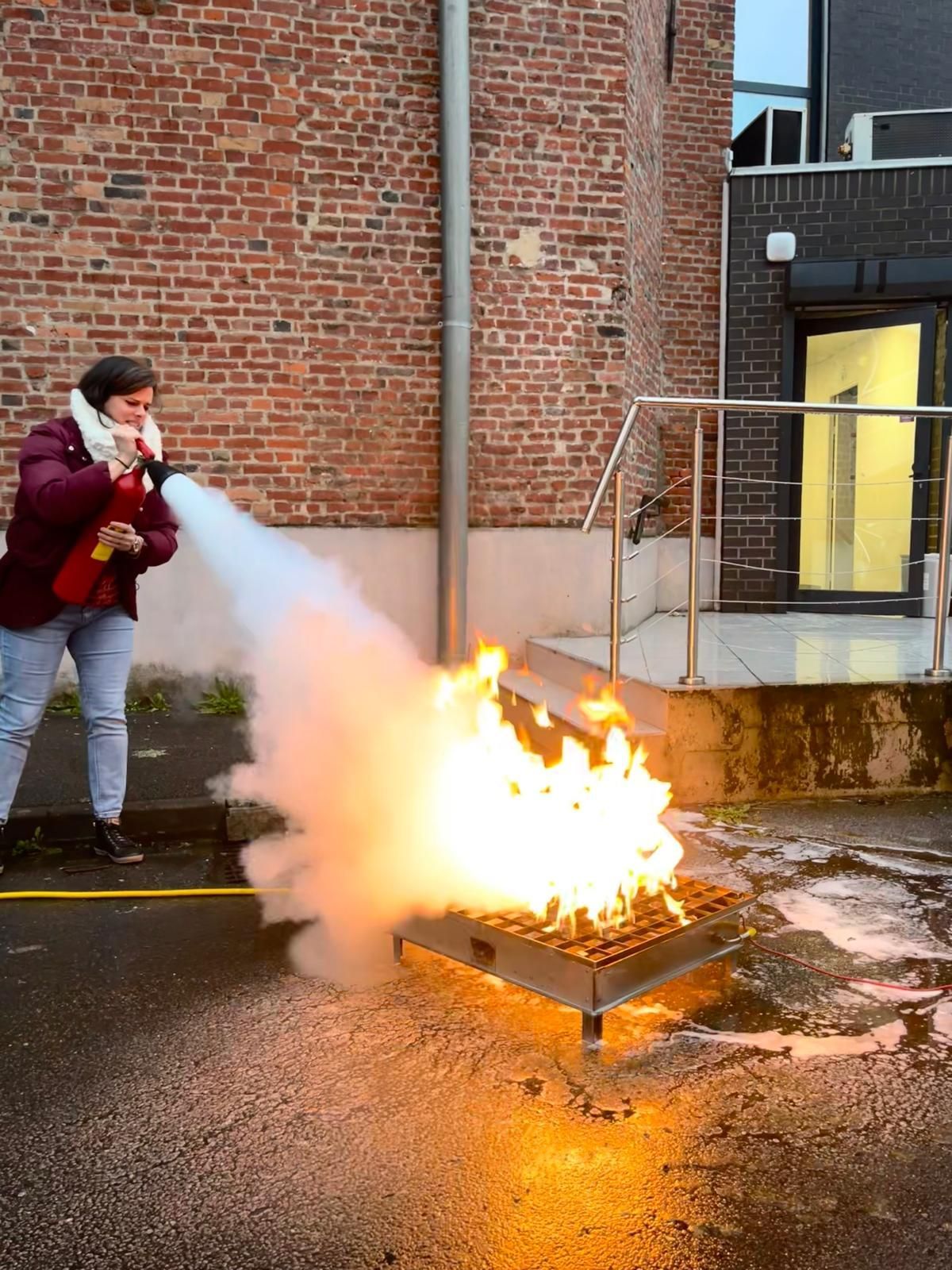 Une femme éteignant un feu lors d'un exercice de prévention.
