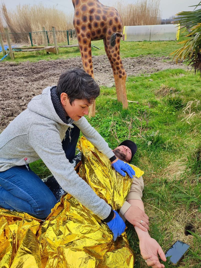 Une femme s'occupant d'un homme couvert d'une couverture de survie.