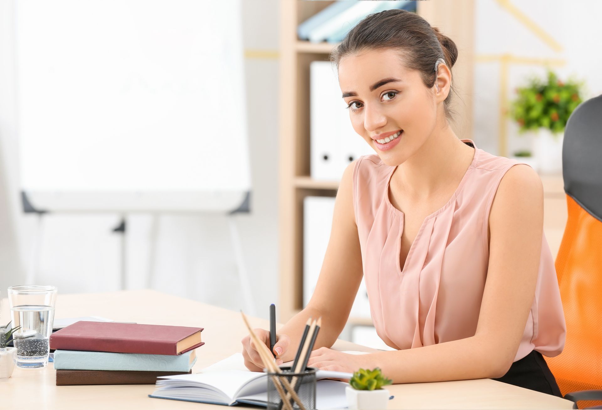 Jeune femme en train d'écrire et portant une aide auditive
