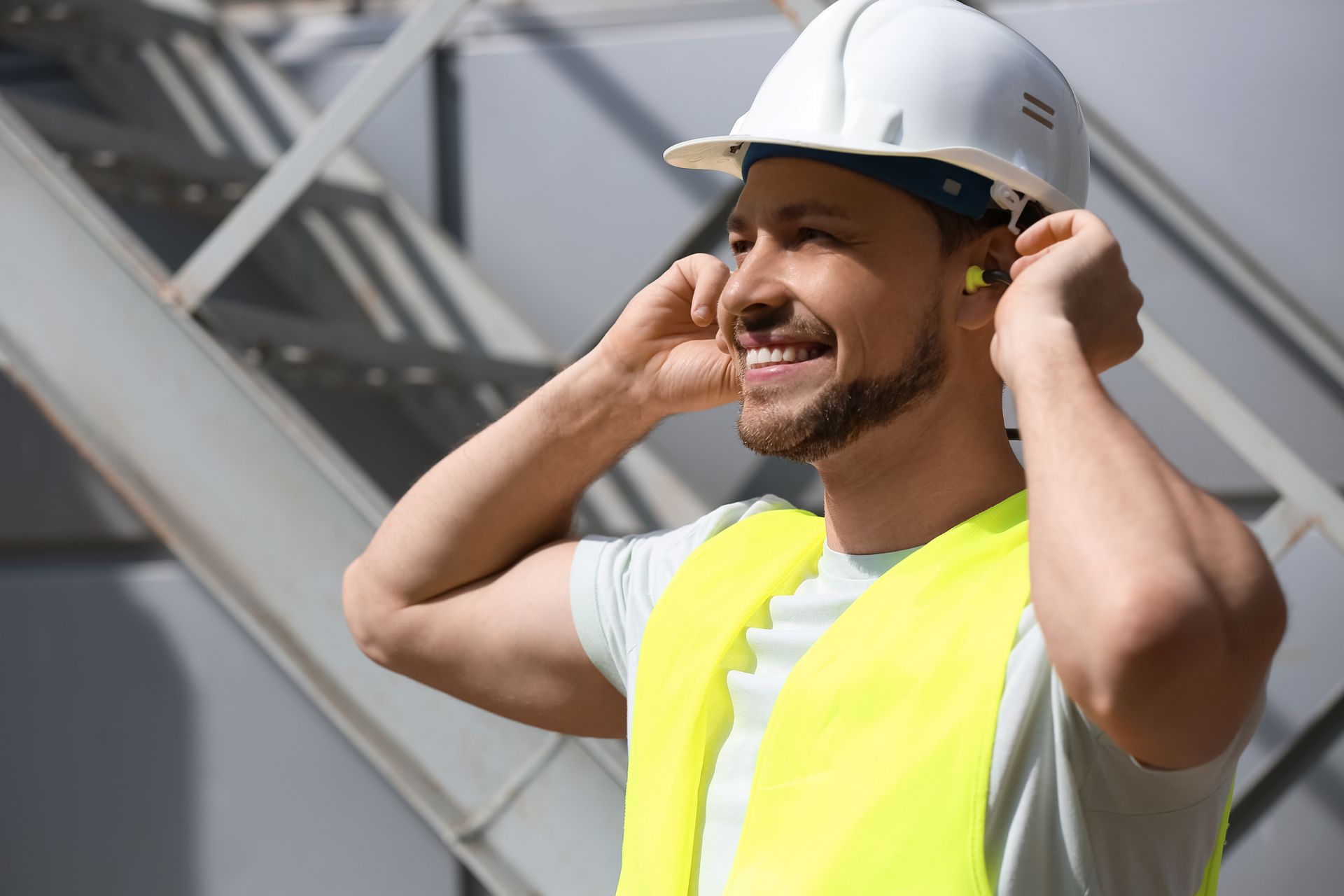 Un homme avec un casque de chantier en train de mettre des protections auditives à ses oreilles