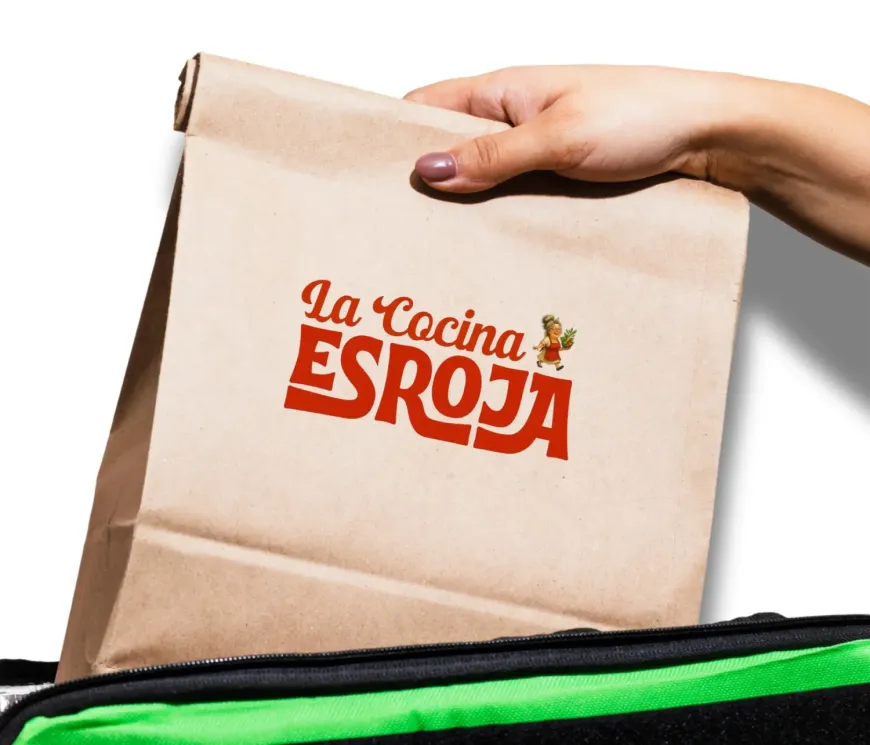 Mano sosteniendo una bolsa de papel marrón con el logo de 