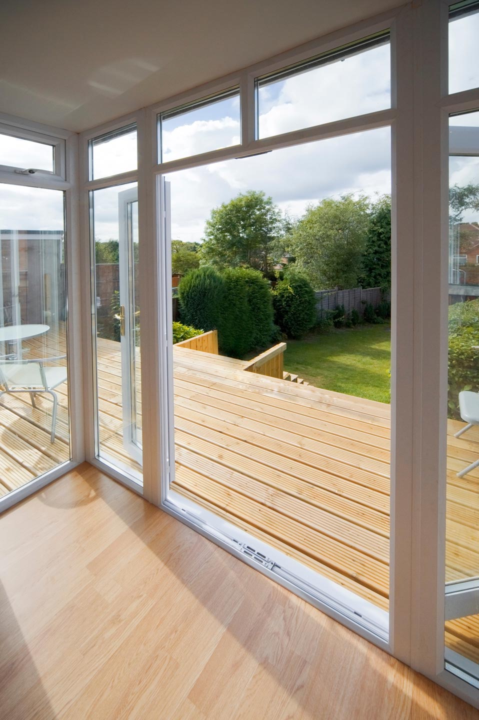 Terrasse en bois clair derrière une baie vitrée