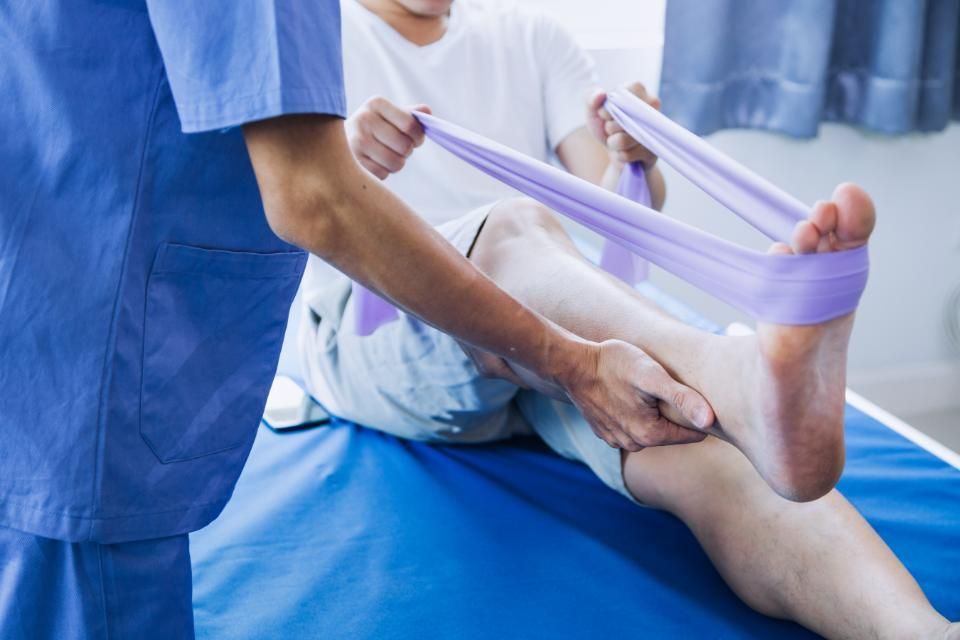 Physios - Ihre Physiotherapeuten - Patient beim Beintraining mit Gummiband