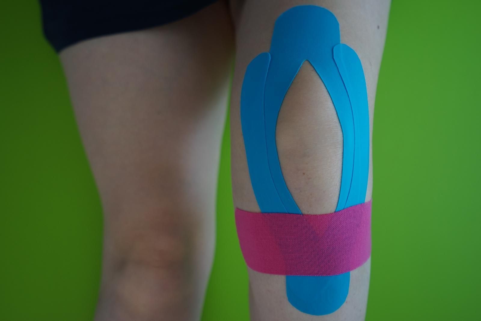 Physios - Ihre Physiotherapeuten - Anbringen von Kinesiotape auf der Schulter einer Patientin