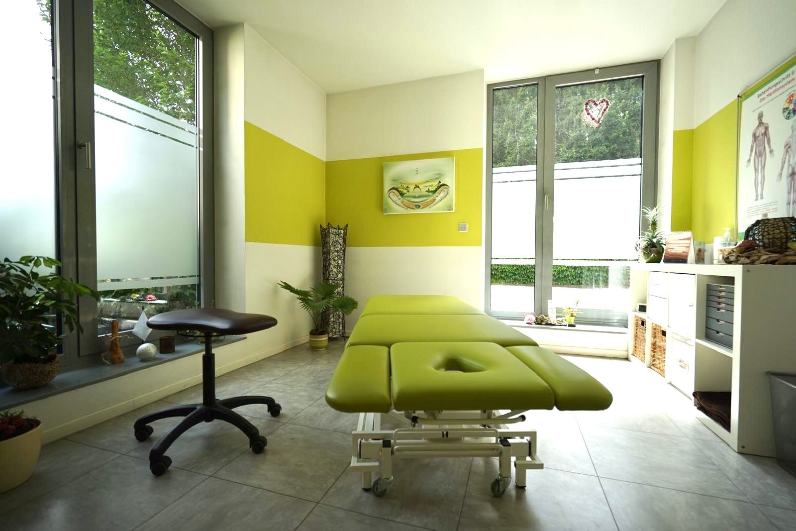Eine grüne Massageliege in einem Raum mit gelben Wänden
