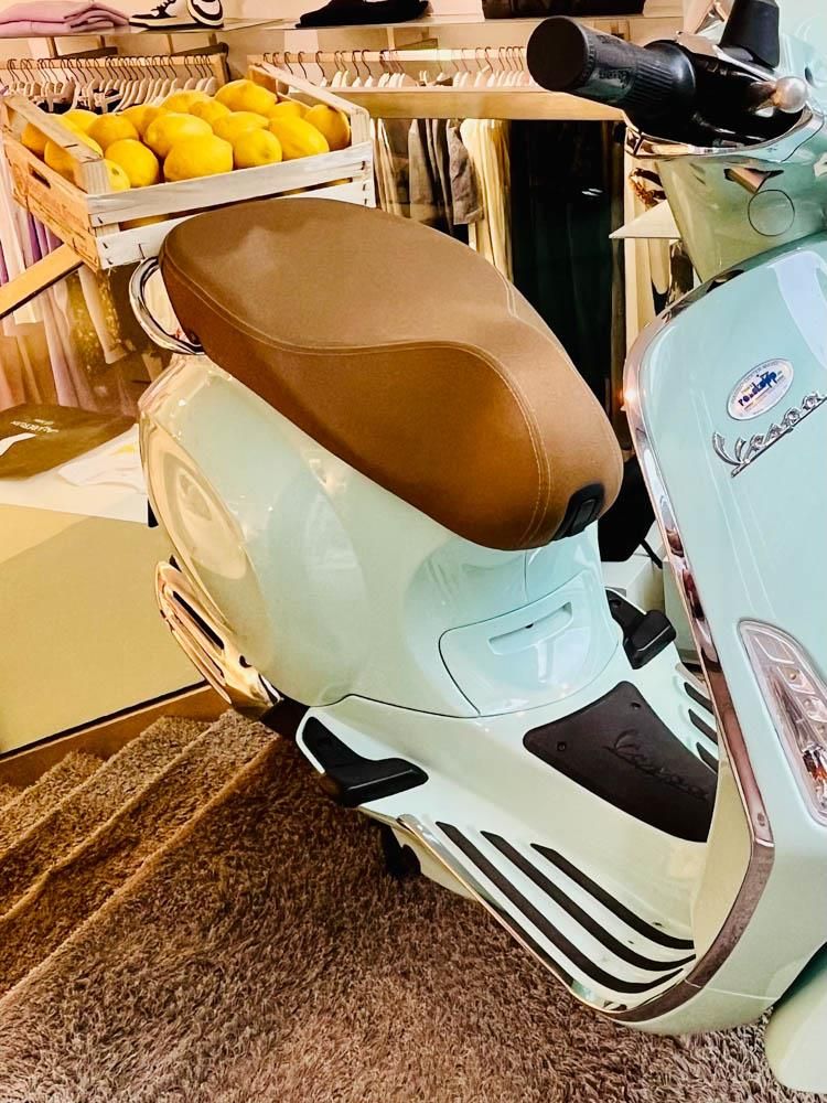 Ein weißer Motorroller mit braunem Sitz steht in einem Geschäft.