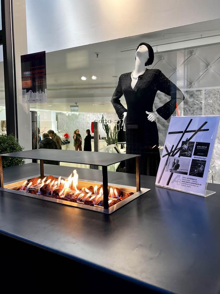 Eine Schaufensterpuppe steht neben einem Kamin auf einem Tisch.