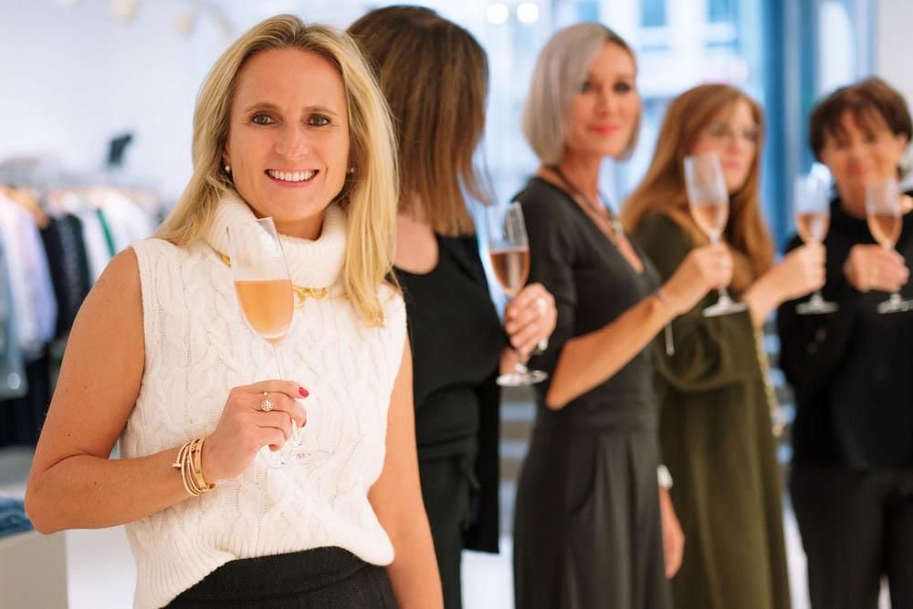 Eine Frau steht vor einer Gruppe von Frauen und hält Weingläser in den Händen.