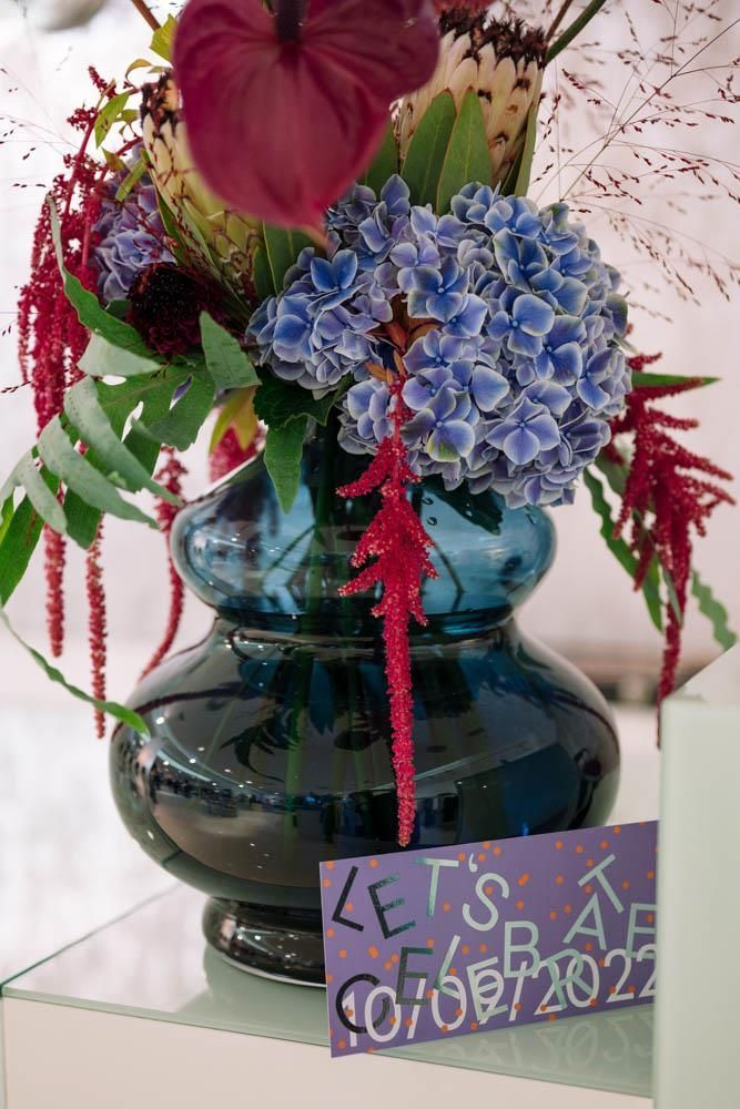 Eine Vase voller Blumen und ein Schild mit der Aufschrift „Lasst uns feiern“