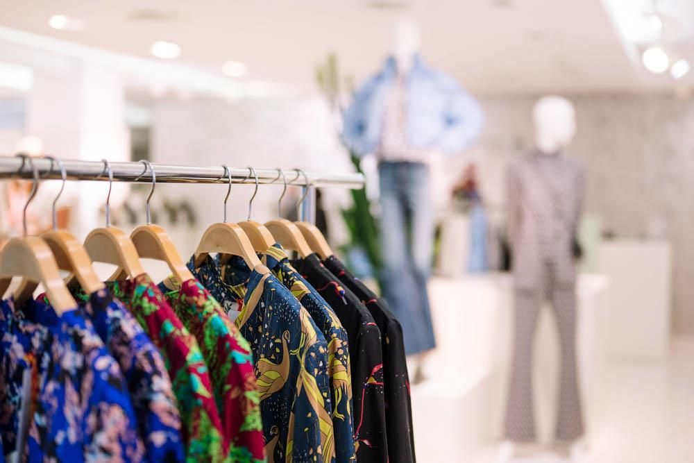 Eine Reihe von Kleidungsstücken, die in einem Geschäft an einer Stange hängen.